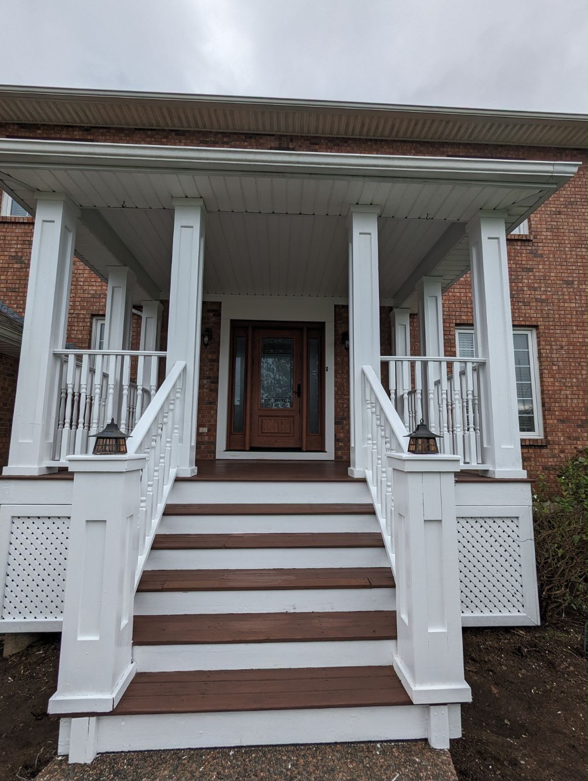 White porch columns, railings, and stained wood stair treads