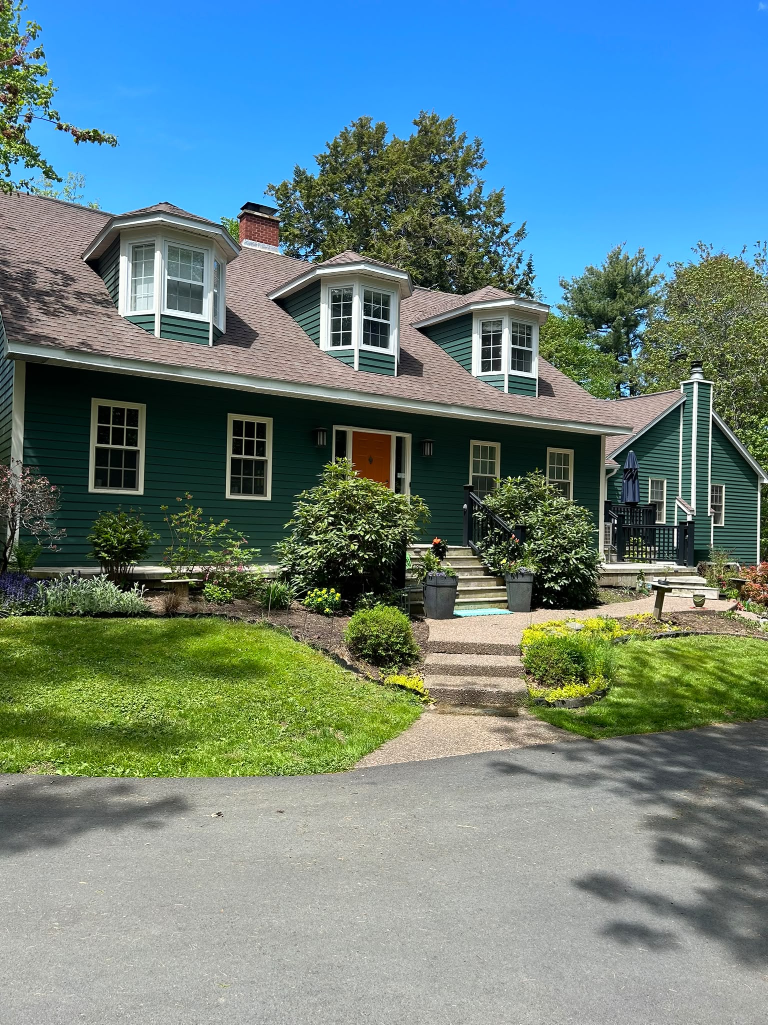 Forest green Cape Cod home with white trim and orange front door