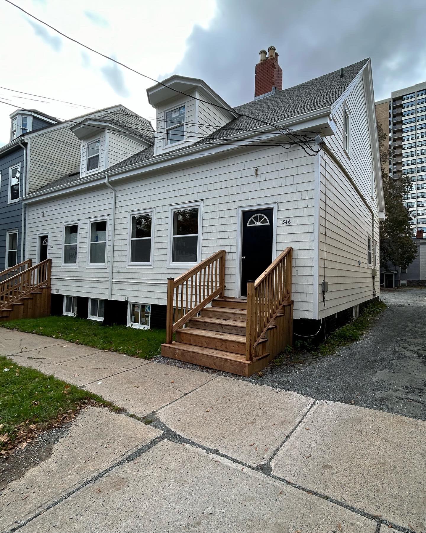 White shingle residential exterior with black doors and wood stairs
